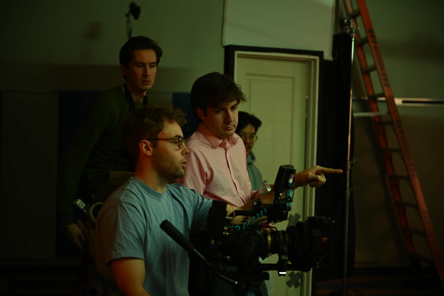 Crew members gather around a camera monitor during production.